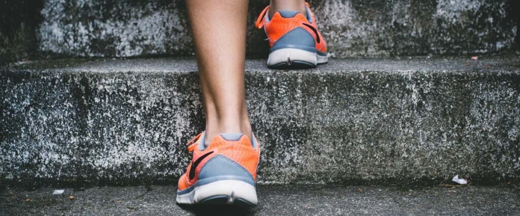 person-med-nike-skor-kliver-upp-på-en-trappa