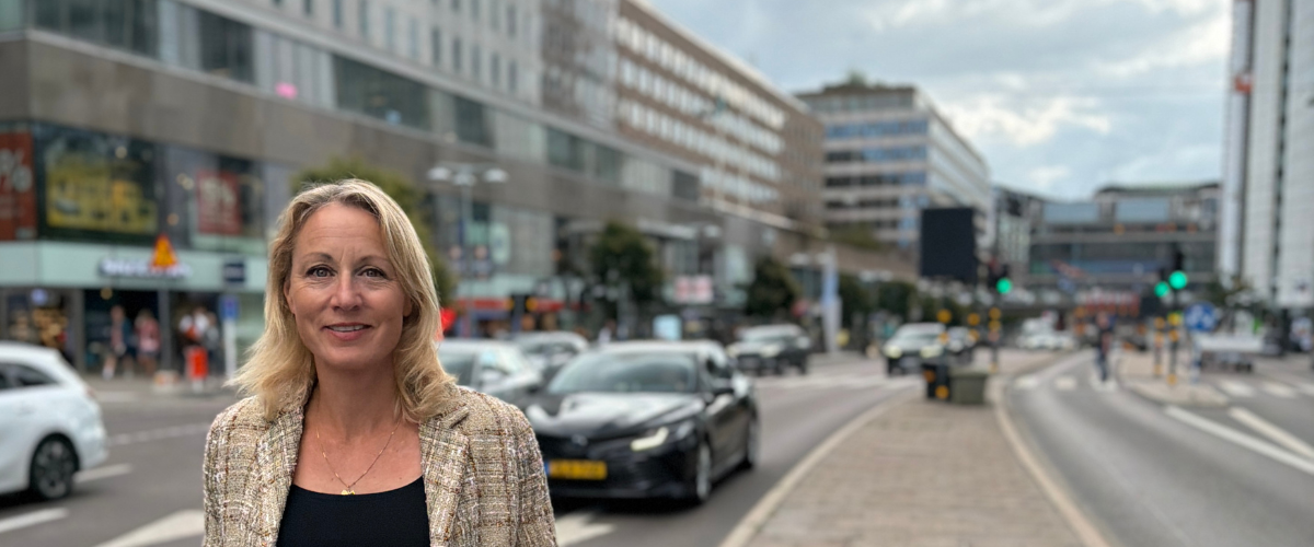 Annika Jepsson, ny VD på Invici står på en stadsgata med trafik och kontorsbyggnader i bakgrunden